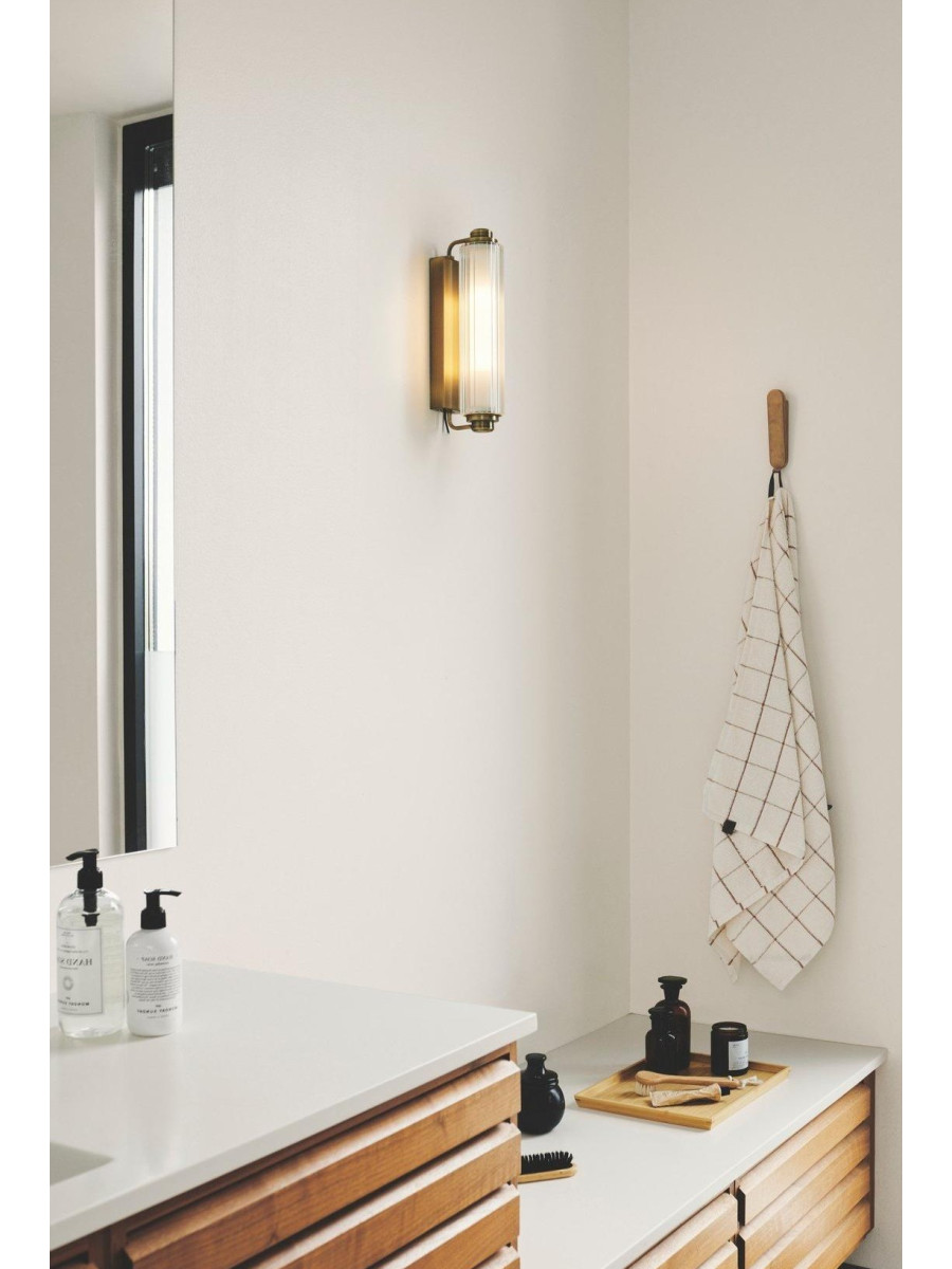 Kinkiet tuba obok lustra w łazience art deco